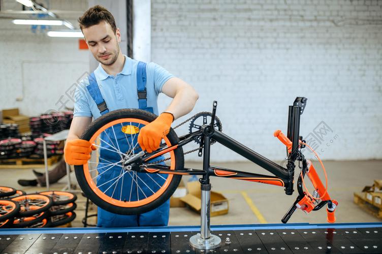 装配线工人,车轮安装穿制服的男技工在车间安装周期零件自行车工厂